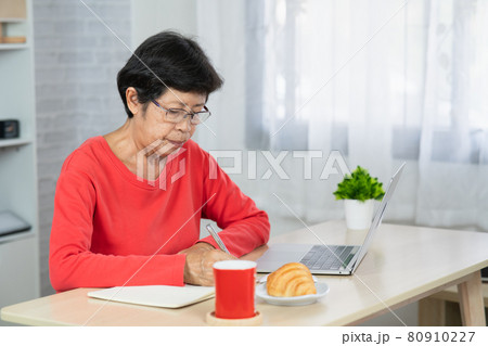 Senior asian woman relaxing using laptop computer while sitting on table. Senior asian woman relaxing using laptop computer while sitting on table. 80910227