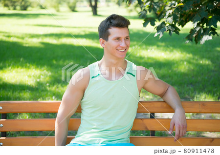 Happy sportsman sitting outdoors on natural landscape Happy sportsman sitting outdoors on natural landscape 80911478