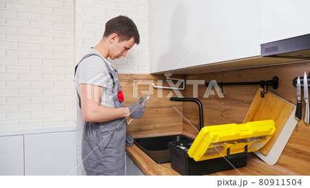 Plumber with toolbox comes to check and fix broken faucet Plumber with toolbox comes to check and fix broken faucet 80911504