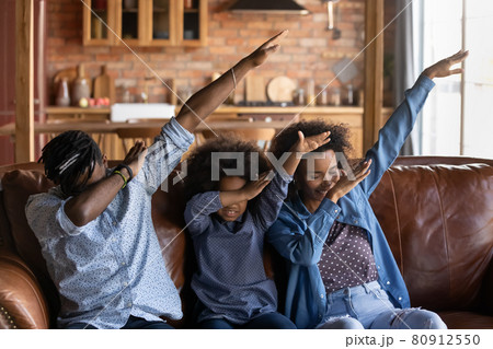 Smiling biracial parents with daughter dab dance 80912550