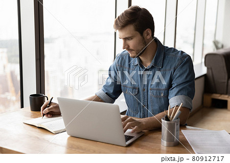 Serious businessman, employee, entrepreneur working at laptop and writing Serious businessman, employee, entrepreneur working at laptop and writing 80912717