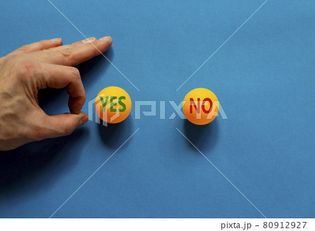 Yes or no symbol. Male hand is about to flick the ball. Orange table tennis balls with words yes no. Beautiful blue background. Business, and yes or no concept. Yes or no symbol. Male hand is about to flick the ball. Orange table tennis balls with words yes no. Beautiful blue background. Business, and yes or no concept. 80912927