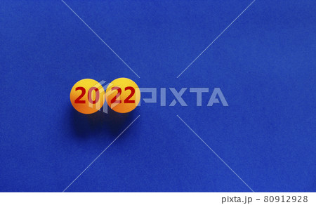 Symbol of the new year 2022. Orange table tennis balls with the number '2022' on a beautiful blue background, copy space. Business and new year 2022 concept. Symbol of the new year 2022. Orange table tennis balls with the number '2022' on a beautiful blue background, copy space. Business and new year 2022 concept. 80912928