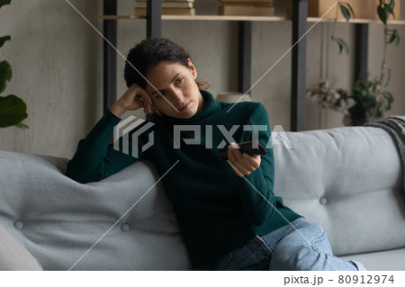 Close up bored woman holding remote tv controller, switching channels 80912974