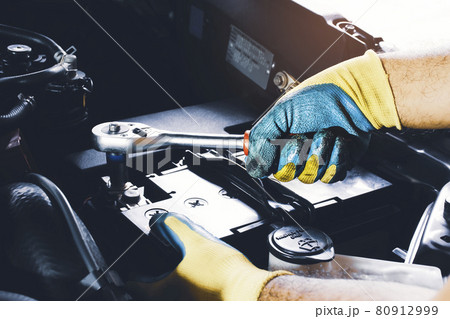 The Mechanic hand is fasten the bolt of battery Anode with socket wrench The Mechanic hand is fasten the bolt of battery Anode with socket wrench 80912999