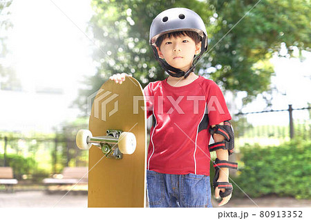スケートボードを持って立つ幼い男の子 80913352
