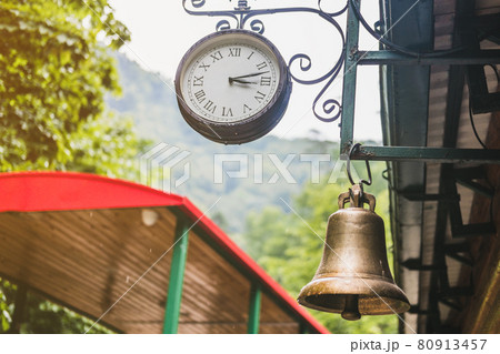 A large clock hangs at the train station in the forest. A large clock hangs at the train station in the forest. 80913457