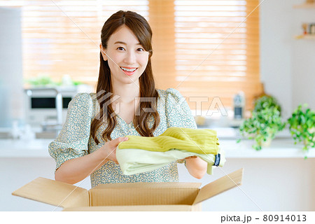 リビングで服を段ボールに詰める若い主婦 リビングで服を段ボールに詰める若い主婦 80914013