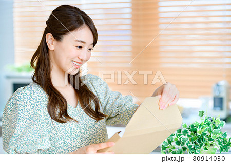 キッチンでメール便の荷物を開ける若い主婦 キッチンでメール便の荷物を開ける若い主婦 80914030