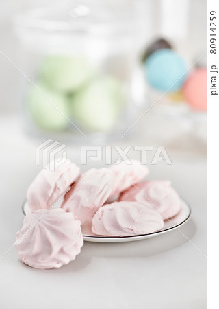 Delicate multi colored marshmallows on white plate. Still life with marshmallows pink on a light table. Delicate multi colored marshmallows on white plate. Still life with marshmallows pink on a light table. 80914259