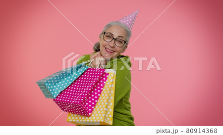Elderly granny woman showing shopping bags, advertising discounts, looking amazed with low prices 80914368
