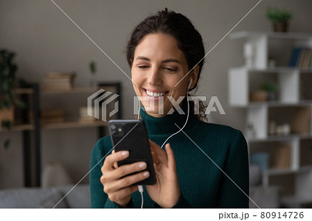 Head shot close up smiling woman in earphones using smartphone Head shot close up smiling woman in earphones using smartphone 80914726
