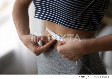 Close up woman using measurement tape, measuring waist, weight loss 80914963