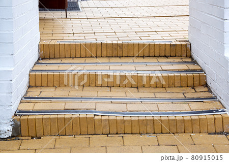 steps with rubber non-slip strips on the arch staircase at the entrance to the white brick building close-up, nobody. steps with rubber non-slip strips on the arch staircase at the entrance to the white brick building close-up, nobody. 80915015