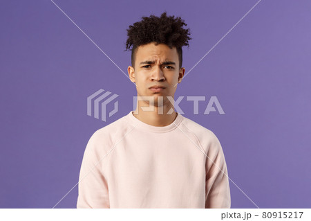 Close-up portrait of skeptical and gloomy, disappointed hispanic young man frowning upset, feel uneasy about bad idea, grimacing with disapproval, standing unhappy purple background 80915217