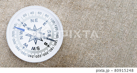 Close-up of compass with sun glare on fabric background Close-up of compass with sun glare on fabric background 80915248