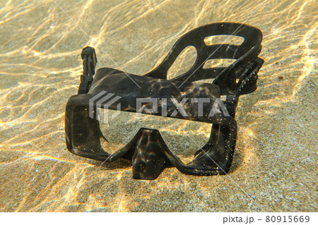 Underwater photo - light from sun refractions at black diving mask sitting in shallow water on clear sand Underwater photo - light from sun refractions at black diving mask sitting in shallow water on clear sand 80915669