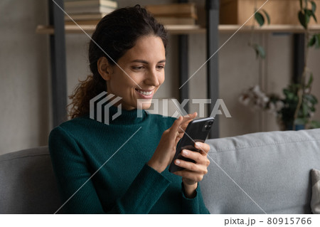 Close up happy young woman using smartphone, relaxing on couch Close up happy young woman using smartphone, relaxing on couch 80915766