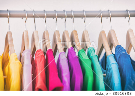 Clothes hanging on clothing rack wardrobe fashion apparel selection of rainbow color t-shirts on closet hangers. Womens wear in store shopping spring cleaning concept. Summer home wardrobe 80916308