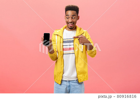 Man being amazed with cool new phone cannot hide happiness from device purchase holding smartphone pointing at gadget screen with excited and impressed face posing over pink background Man being amazed with cool new phone cannot hide happiness from device purchase holding smartphone pointing at gadget screen with excited and impressed face posing over pink background 80916816