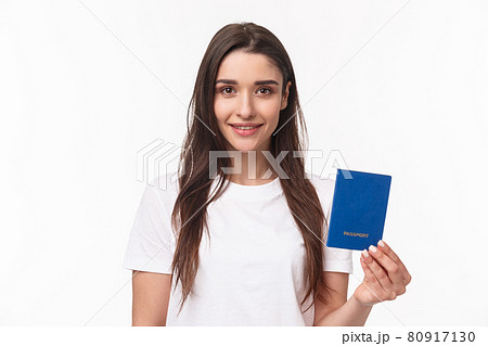 Travelling, holidays, summer concept. Close-up portrait of caucasian smiling happy woman in t-shirt, holding passport with and looking camera, buying flight ticket waiting for her plane in terminal Travelling, holidays, summer concept. Close-up portrait of caucasian smiling happy woman in t-shirt, holding passport with and looking camera, buying flight ticket waiting for her plane in terminal 80917130