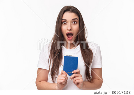 Travelling, holidays, summer concept. Close-up portrait of impressed, shocked young woman holding passport, drop jaw and staring astonished at camera, ready to travel, moving abroad 80917138