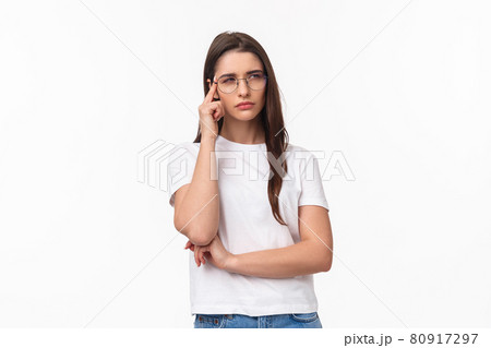 Waist-up portrait of doubtful attractive brunette girl looking focused and suspicious, thinking squinting and looking away while processing information with disbelief and doubt, white background 80917297