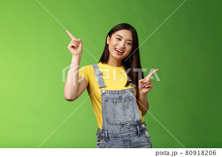 Friendly stylish good-looking upbeat teenage asian brunette, dancing joyfully showing few choices, shopping online easy picking products, pointing sideways left right, smiling enthusiastic 80918206