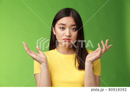 Close-up confused unemotive brunette woman spread hands sideways full dibelief, questioned what happening, look apathy reluctant, stand green background frustrated, no emotions 80918392