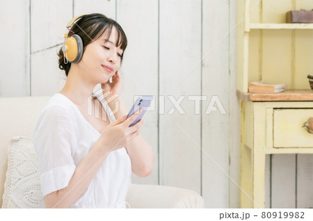 ソファーに座ってヘッドホンで音楽を聴く若い女性 ソファーに座ってヘッドホンで音楽を聴く若い女性 80919982