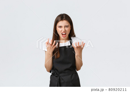 Grocery store employees, small business and coffee shops concept. Mad saleswoman complaining on rude customers, clench hands angry and grimacing angry, standing white background 80920211