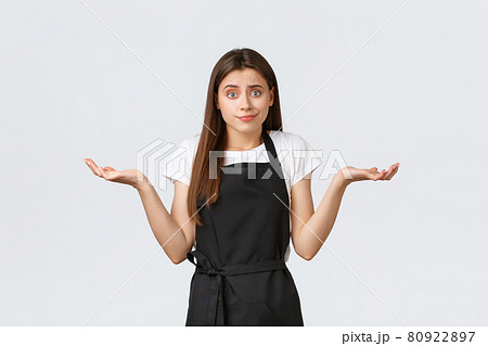 Grocery store employees, small business and coffee shops concept. Indecisive and clueless barista in black apron shrugging uncertain. Saleswoman having no idea what say 80922897