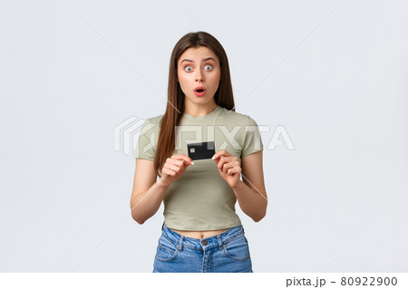 Shopping mall, lifestyle and fashion concept. Shocked and astonished caucasian female buyer, customer in store holding credit card and stare surprised at awesome special discounts 80922900