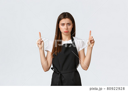 Small business, employees and coffee shop concept. Gloomy and sad cute waitress pointing fingers up and sulking upset. Silly barista in black apron complaining over bad news on top banner 80922928