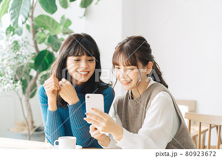 カフェでスマホを見る笑顔の女性2人組 80923672