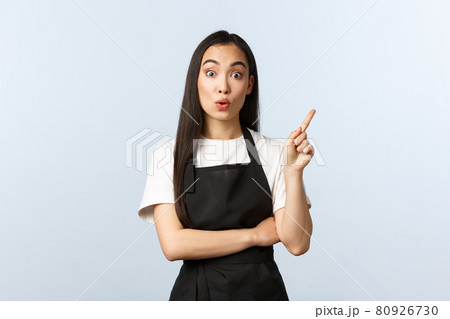 Coffee shop, small business and startup concept. Asian barista have idea, raise index finger, say suggestion, make-up plan, sharing thought and pointing upper right corner, working in cafe 80926730