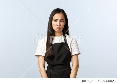 Coffee shop, small business and startup concept. Gloomy and sad cute asian barista, female cafe staff sulking, feeling distressed or exhausted, have unhappy expression, white background 80926802