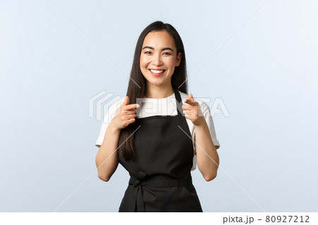 Coffee shop, small business and startup concept. Cheerful smiling female barista, asian cafe staff in black apron pointing at camera, inviting consumers visit and try new desserts, white background Coffee shop, small business and startup concept. Cheerful smiling female barista, asian cafe staff in black apron pointing at camera, inviting consumers visit and try new desserts, white background 80927212