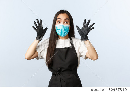 Covid-19, social distancing, small coffee shop business and preventing virus concept. Ambushed and worried young asian employee, cafe worker in medical mask and gloves raise hands up excited Covid-19, social distancing, small coffee shop business and preventing virus concept. Ambushed and worried young asian employee, cafe worker in medical mask and gloves raise hands up excited 80927310