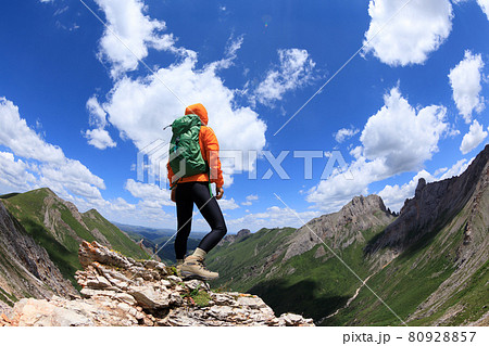 Successful woman backpacker hiking on sunset alpine mountain peak 80928857