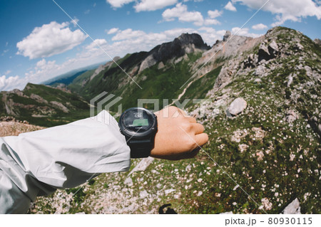 Hiker on high altitude mountain top checking the altimeter on the sports watch Hiker on high altitude mountain top checking the altimeter on the sports watch 80930115