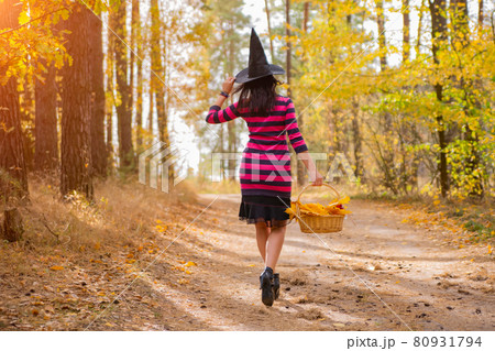 young attractive witch walks in the autumn orange forest.helloween concept. 80931794