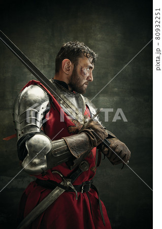 Side view. Portrait of one brutal bearded man, medeival warrior or knight with dirty wounded face holding sword Side view. Portrait of one brutal bearded man, medeival warrior or knight with dirty wounded face holding sword 80932251