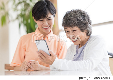 介護イメージ　スマホを見るシニア女性と介護士のポートレート 80932863