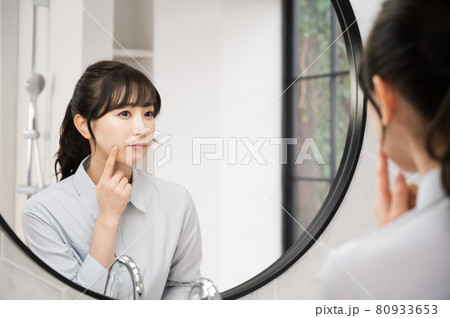 バスルームの鏡の前でお肌のチェックをする女性 バスルームの鏡の前でお肌のチェックをする女性 80933653