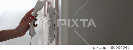 Woman hand picking up phone in hotel corridor closeup Woman hand picking up phone in hotel corridor closeup 80934040