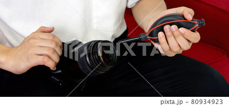 Young photographer cleaning the camera and lens with a air blower camera cleaning after shooting fashion models in the studio. Young photographer cleaning the camera and lens with a air blower camera cleaning after shooting fashion models in the studio. 80934923