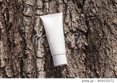 Organic cosmetic cream in tube on a tree bark natural background. Beauty product packaging mockup. Cream bottle, lotion, mousse, shampoo for skincare routine. Copy space, top view. 80935072
