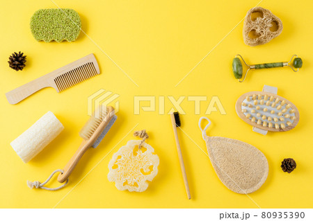Jade face roller, anti cellulite massager, loofah and bamboo sponges, hairbrush, wooden comb on yellow surface. Tools for beauty routine from ecological material. Zero waste bath. Jade face roller, anti cellulite massager, loofah and bamboo sponges, hairbrush, wooden comb on yellow surface. Tools for beauty routine from ecological material. Zero waste bath. 80935390