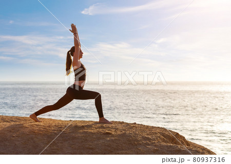 Young fitness woman practicing yoga at the seashore in the morning Young fitness woman practicing yoga at the seashore in the morning 80937316